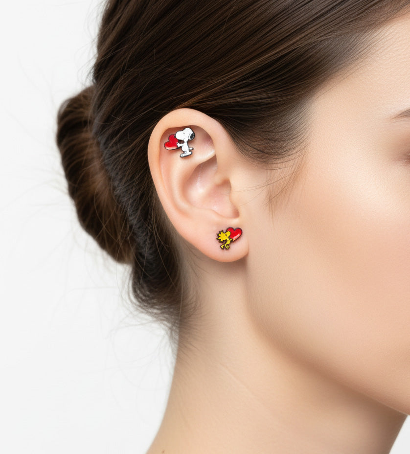 Snoopy and Woodstock earrings worn on different ear piercings – cute mismatched styling.