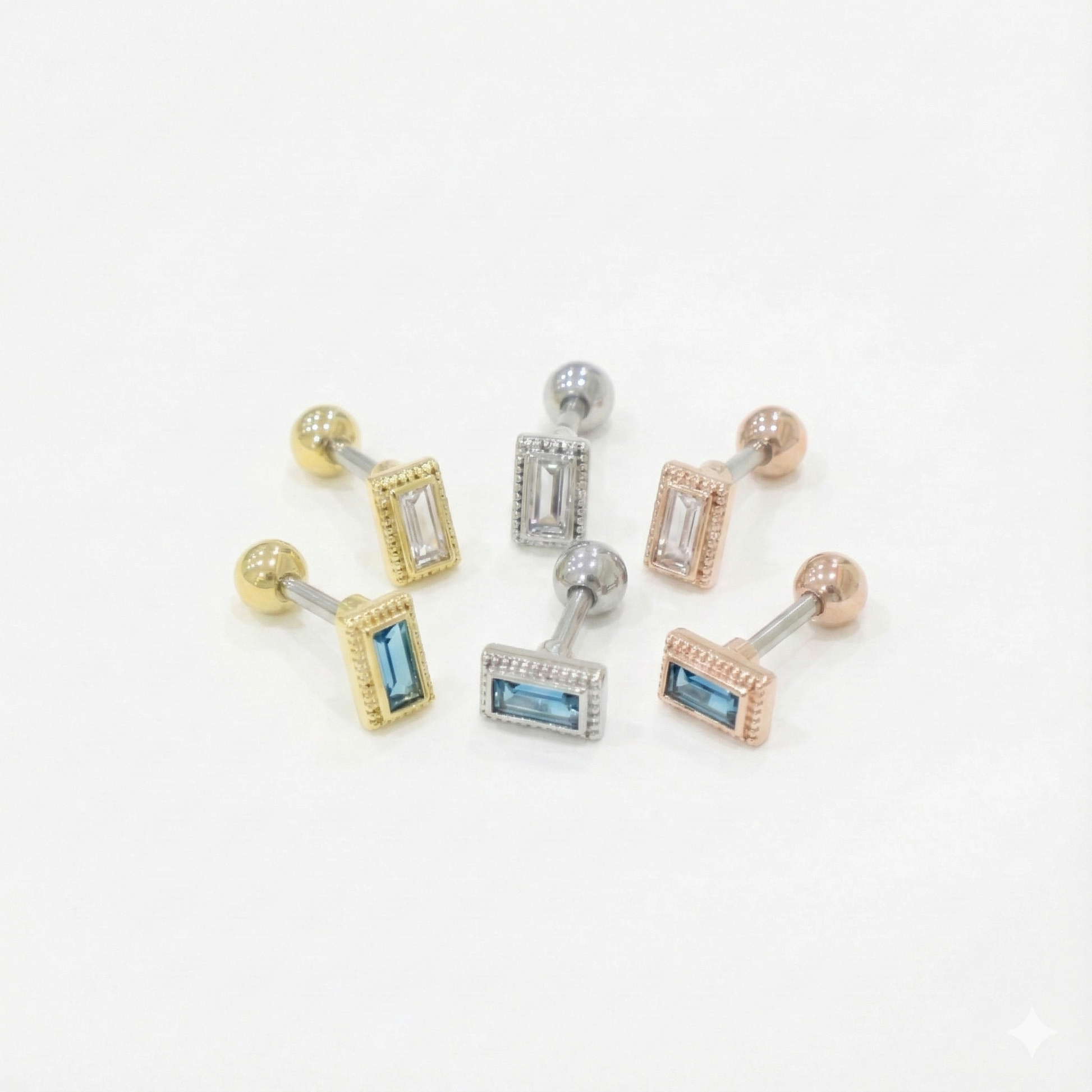 A set of six barbell earrings featuring rectangular CZ stones in clear and blue, with gold, silver, and rose gold bezel settings.