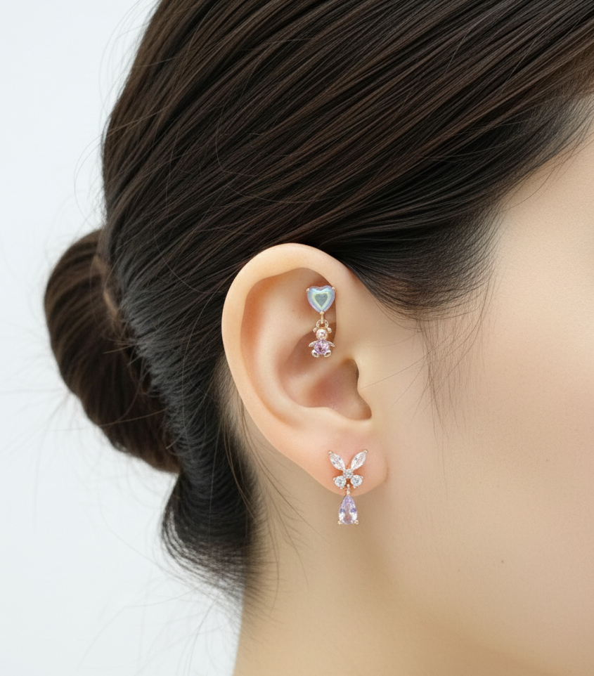 Close-up of a person wearing a heart-shaped earring and a floral earring on a plain background