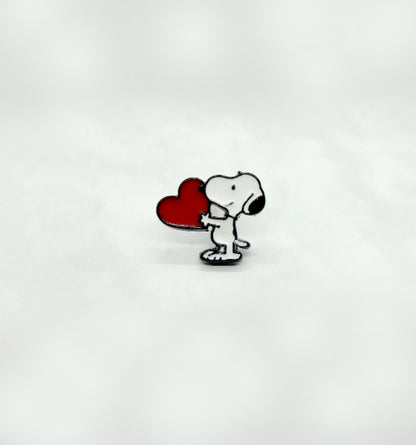 Solo Snoopy enamel earring holding a red heart, photographed upright on white fabric.