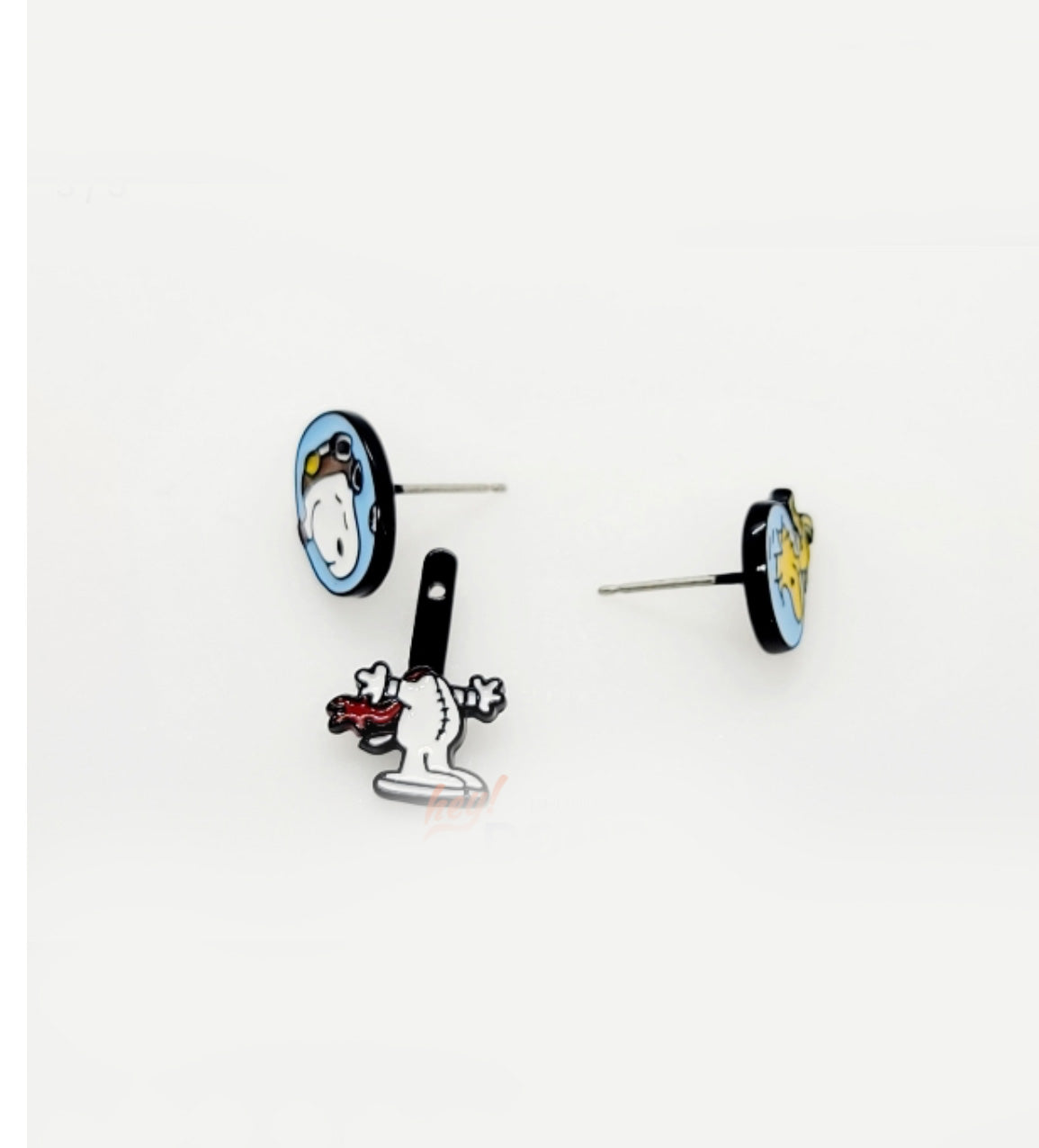 Flat-lay of two post-back earrings — Snoopy in a helmet with dangling body piece, and Woodstock in a matching helmet — placed on a white surface.