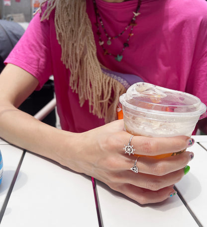 Hand holding iced tea wearing silver steering wheel ring summer lifestyle