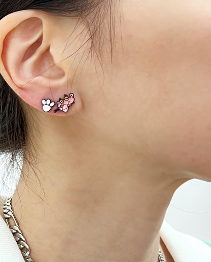 Model wearing Pink Panther head and white paw stud earrings, close-up on earlobe, styled with a silver chain necklace