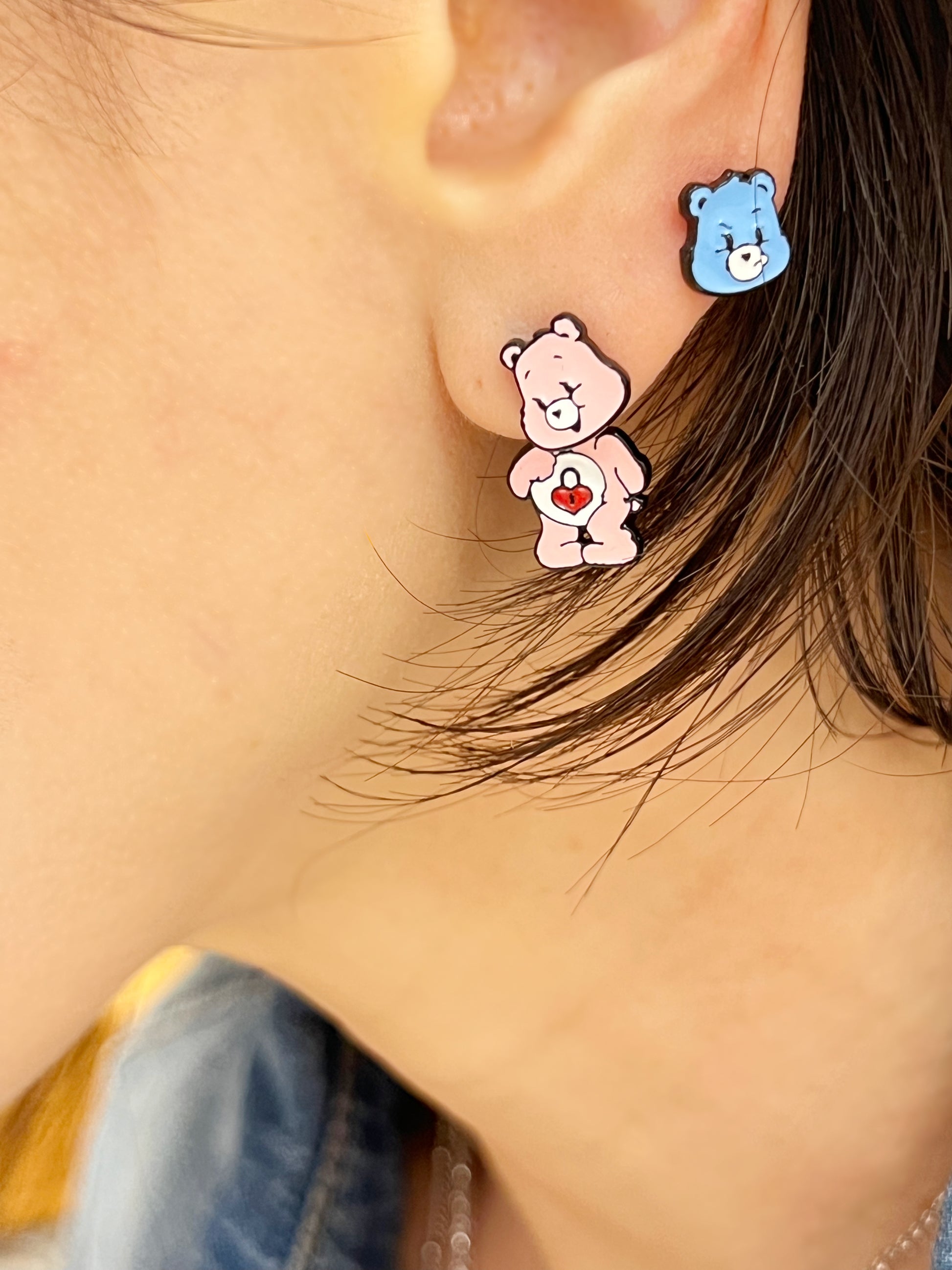 Pink bear earring set worn on both lobes, styled with a denim jacket and delicate silver necklace layered underneath.