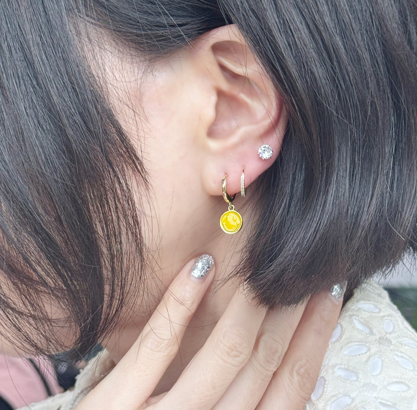 Y2K smiley face earrings worn on ear showing asymmetric styling
