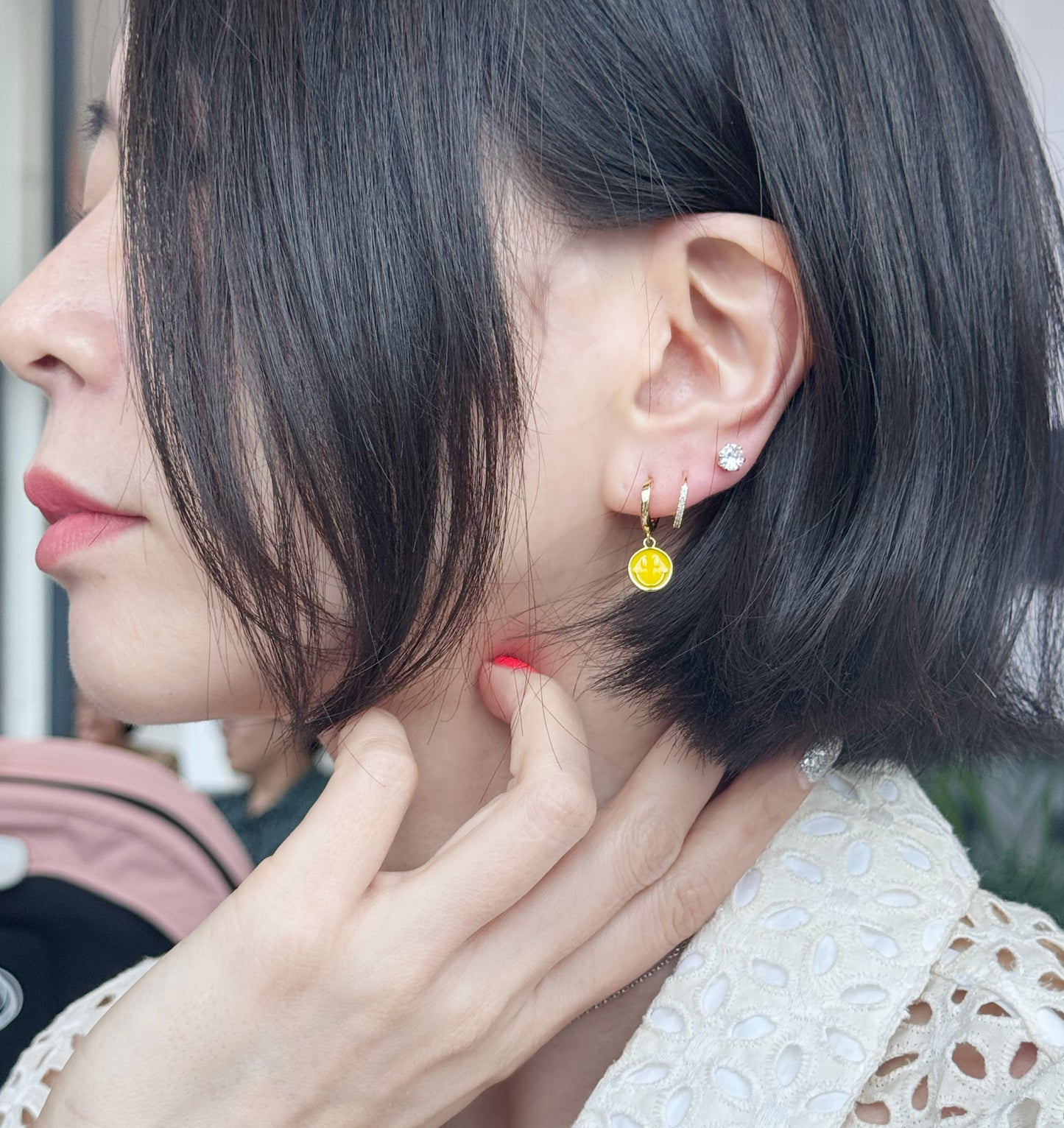 Asymmetric drop hoop earrings with smiley face charm close up