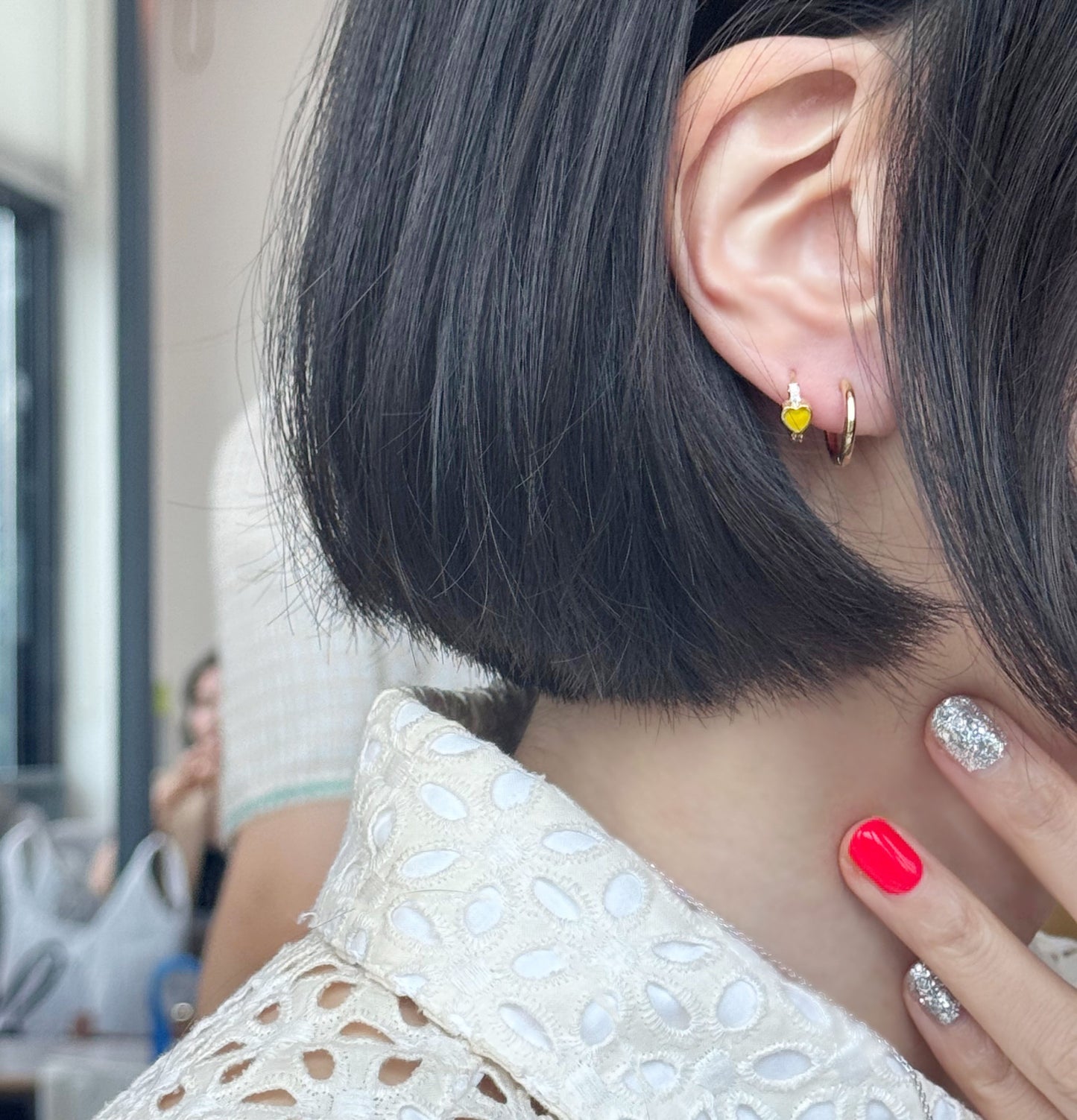 Gold huggie hoop earrings with smiley charm worn on ear