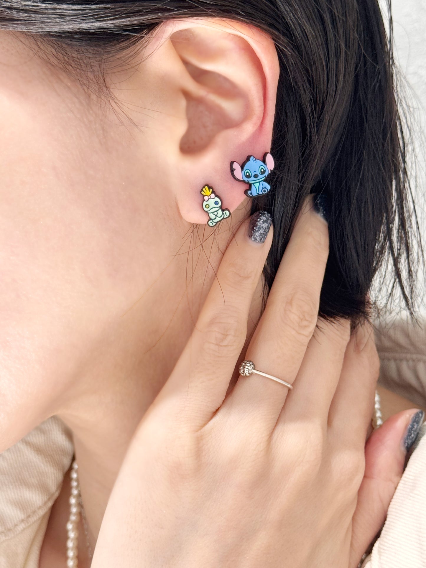 Stitch and Scrump character stud earrings worn on left ear, silver post, playful Korean handmade design.
