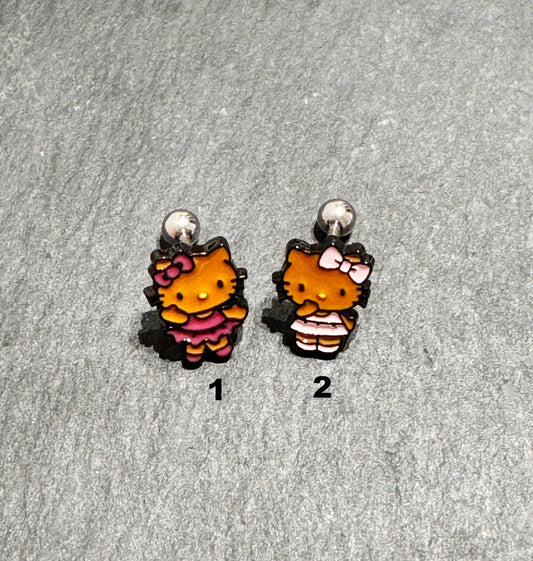 Adorable Hello Kitty–inspired piercing featuring a playful Hawaii-style cat in pink or red dress. Made with hypoallergenic surgical steel. Sold as single.