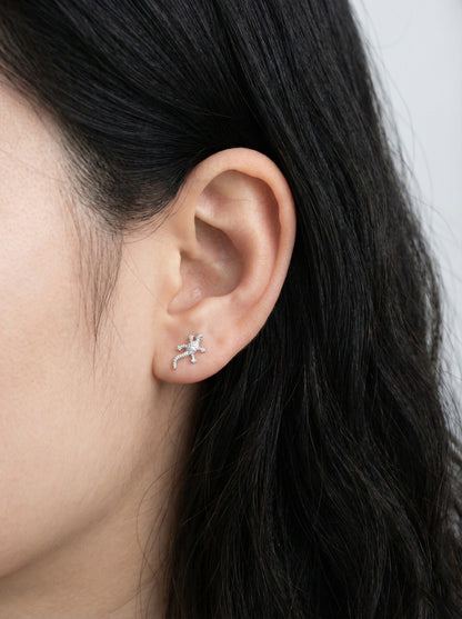 Close-up of an ear wearing a silver earring with a white background