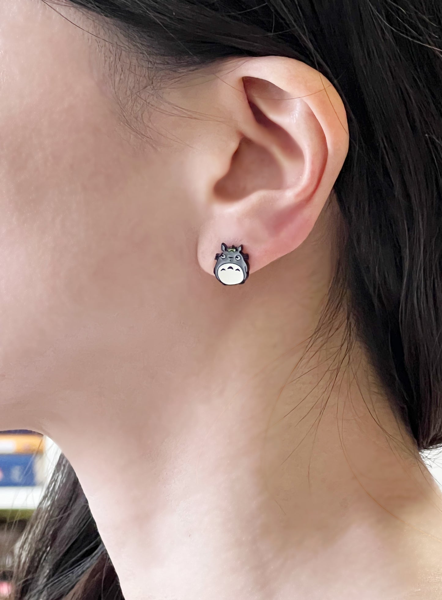 Woman wearing Totoro stud earring on left earlobe close-up shot