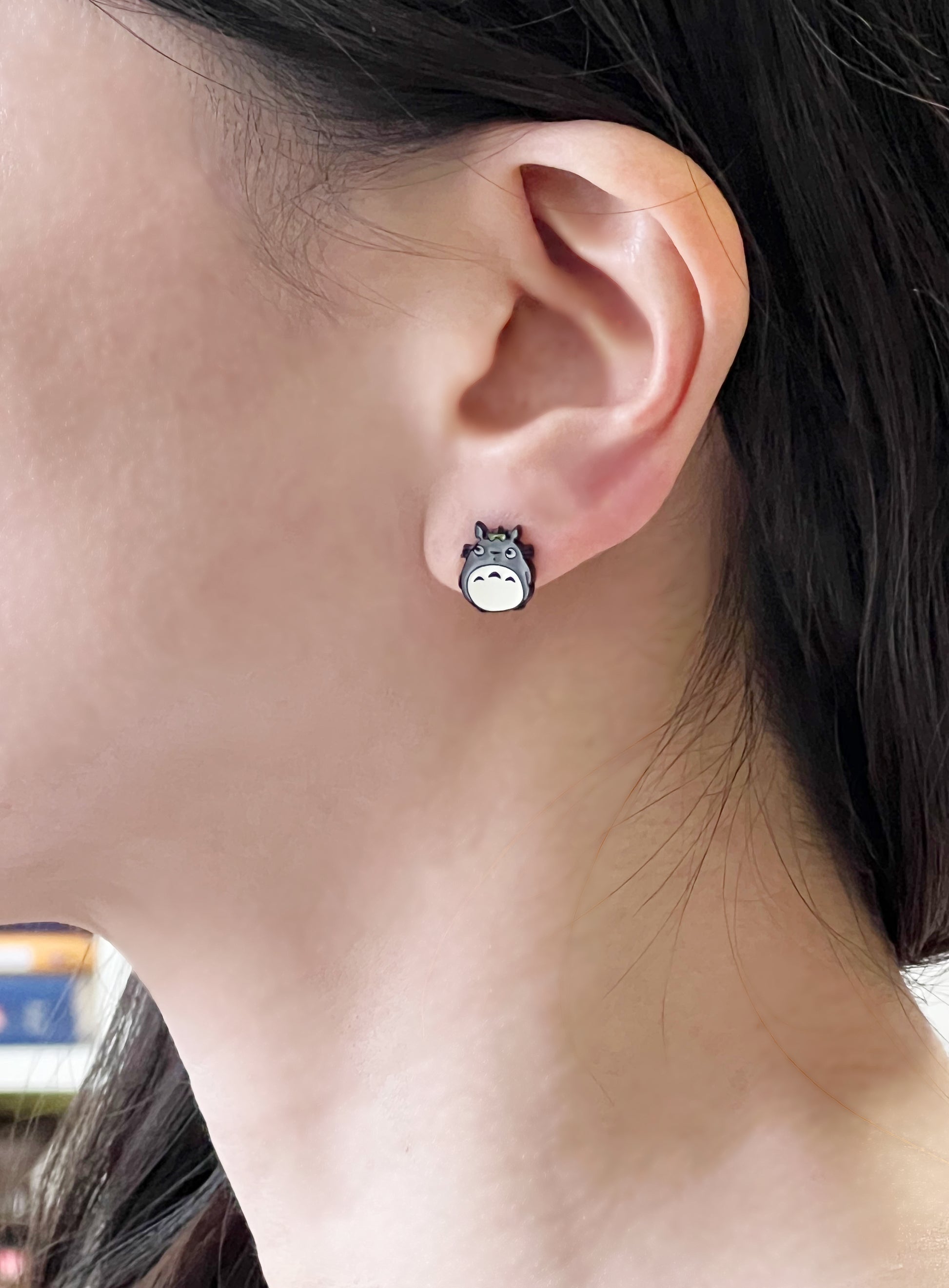 Woman wearing Totoro stud earring on left earlobe close-up shot