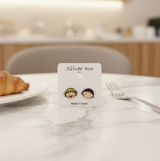 Lifestyle shot of anime earrings on packaging card with croissant on marble table - Made in Korea