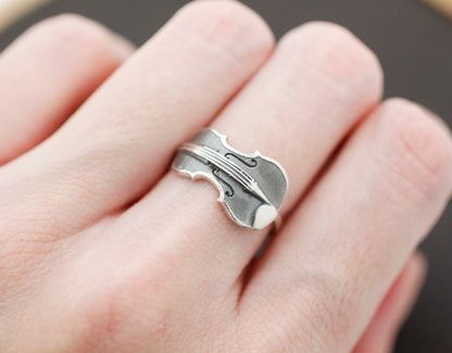 Violin-shaped silver ring worn on hand, oxidized classic finish