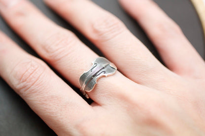 Close-up of handmade violin silver ring on finger.