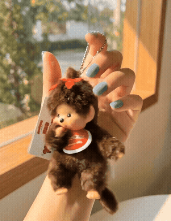 Hand holding Monchhichi Classic Boy plush keychain with blue nail polish showing size reference — vintage Y2K kawaii accessory