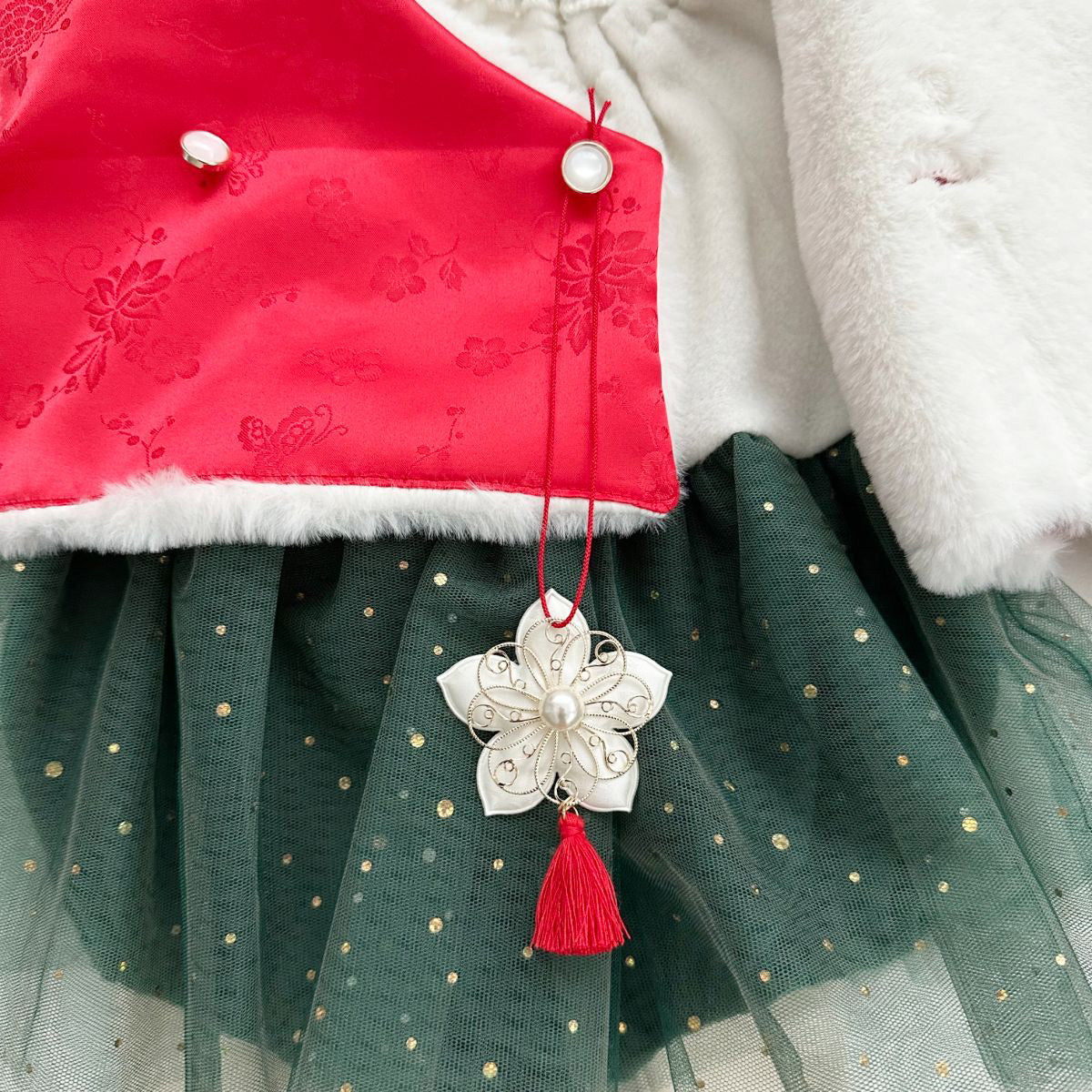 Korean hanbok-style baby outfit with a Santa-inspired holiday color palette, featuring a traditional norigae tassel accessory.