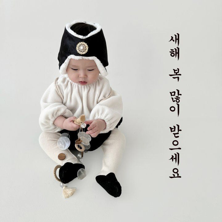 Baby in a black Korean jobawi bonnet with a brooch, holding shiny coins, with New Year's greeting in Korean text.