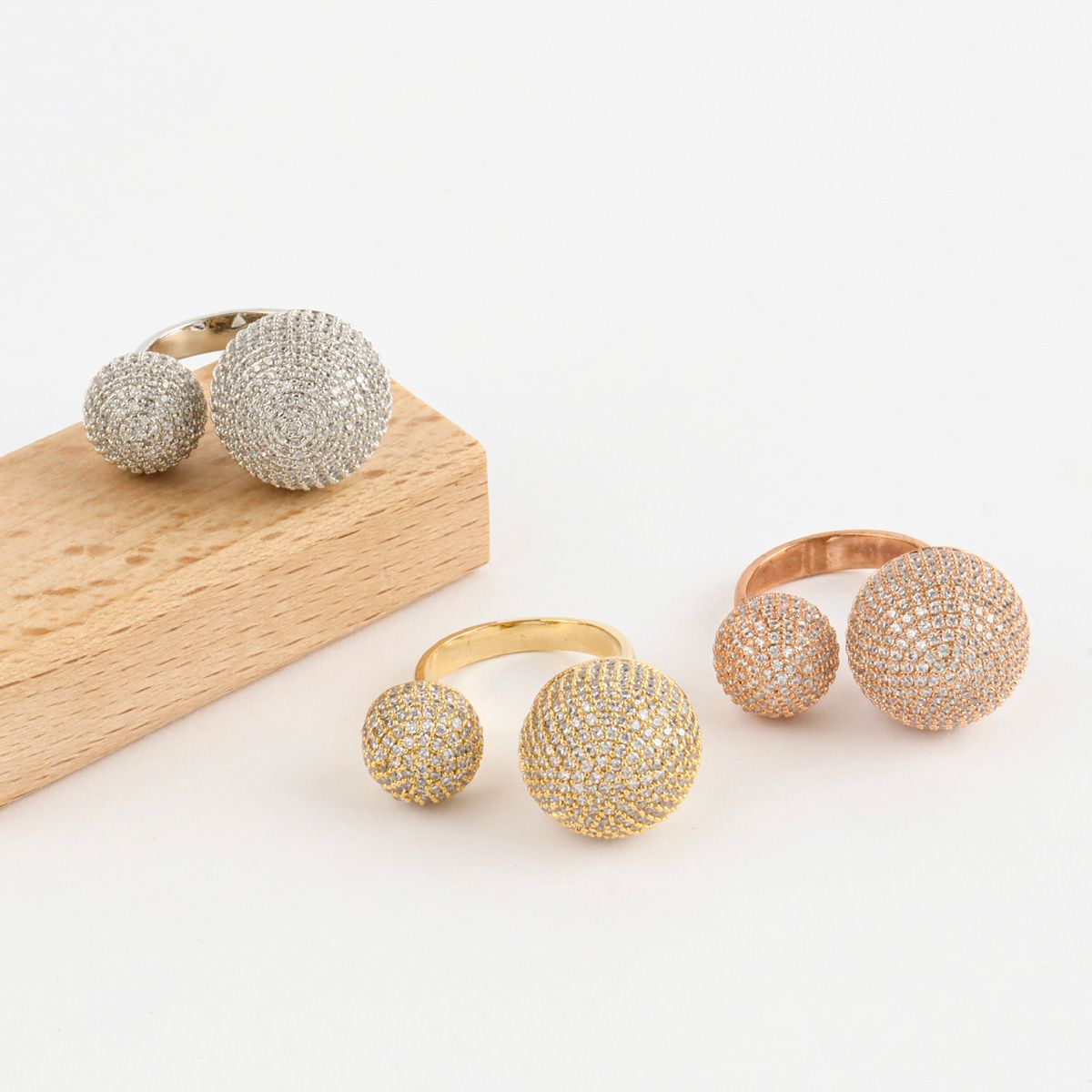 Crystal dome open rings in silver, gold, and rose gold displayed on minimal wood block