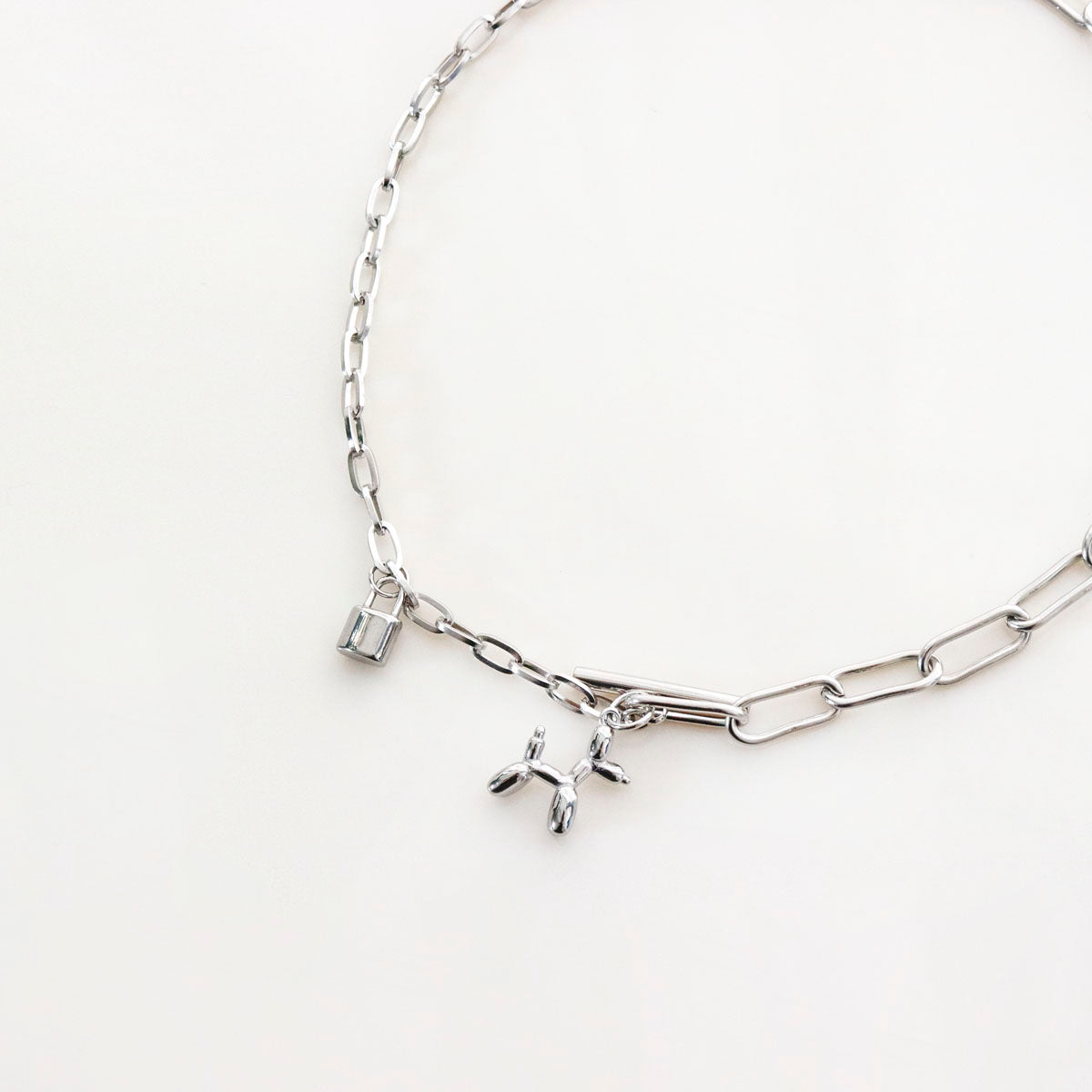 Silver surgical steel mixed chain necklace with balloon dog and padlock charms on white background