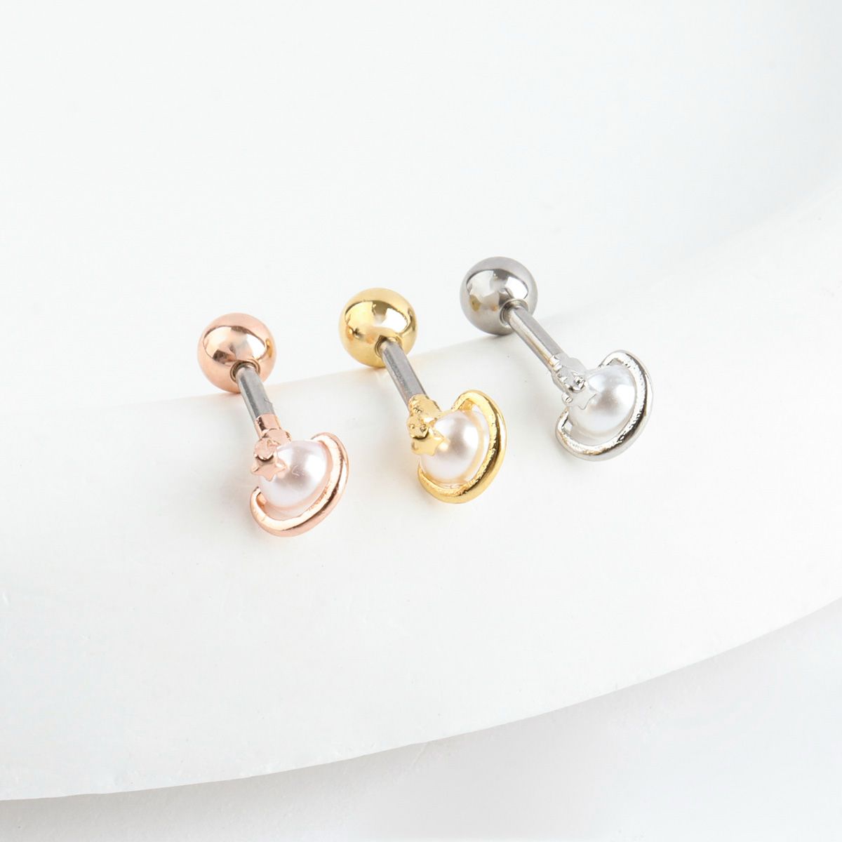 Three color options of Saturn planet barbell piercing - silver, gold, and rose gold finishes