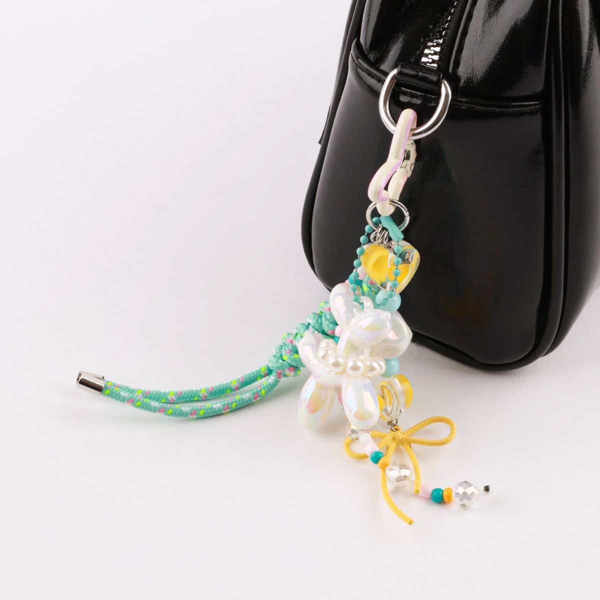 White pearl balloon dog keychain detail shot on black patent leather bag