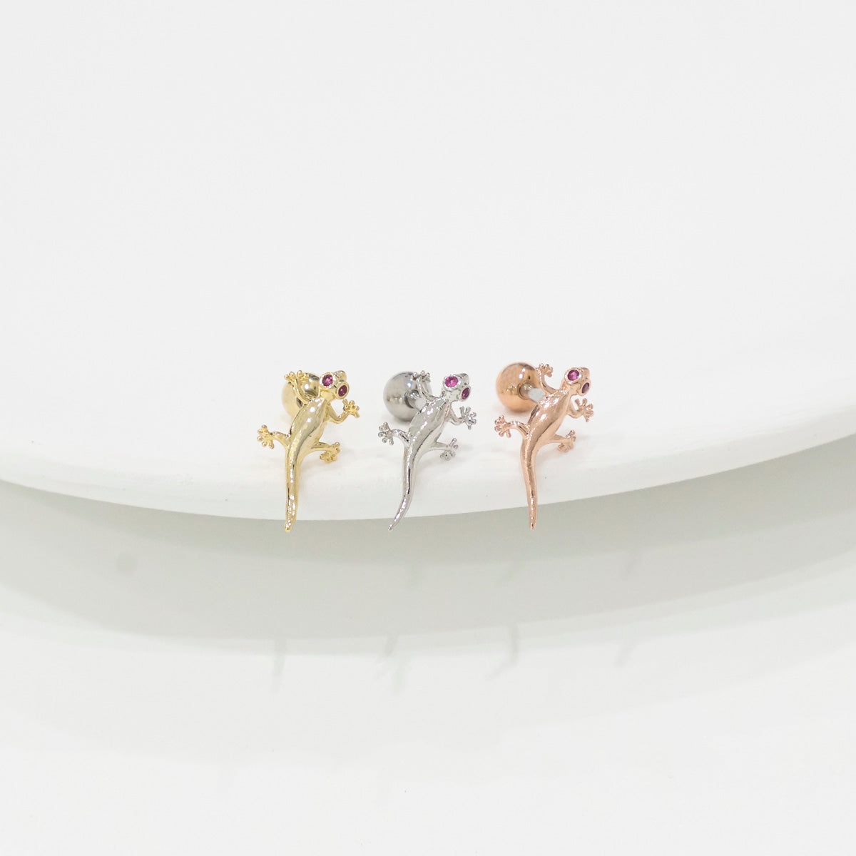Three sleek gecko lizard piercings in gold silver rose gold showing smooth plain design without crystals