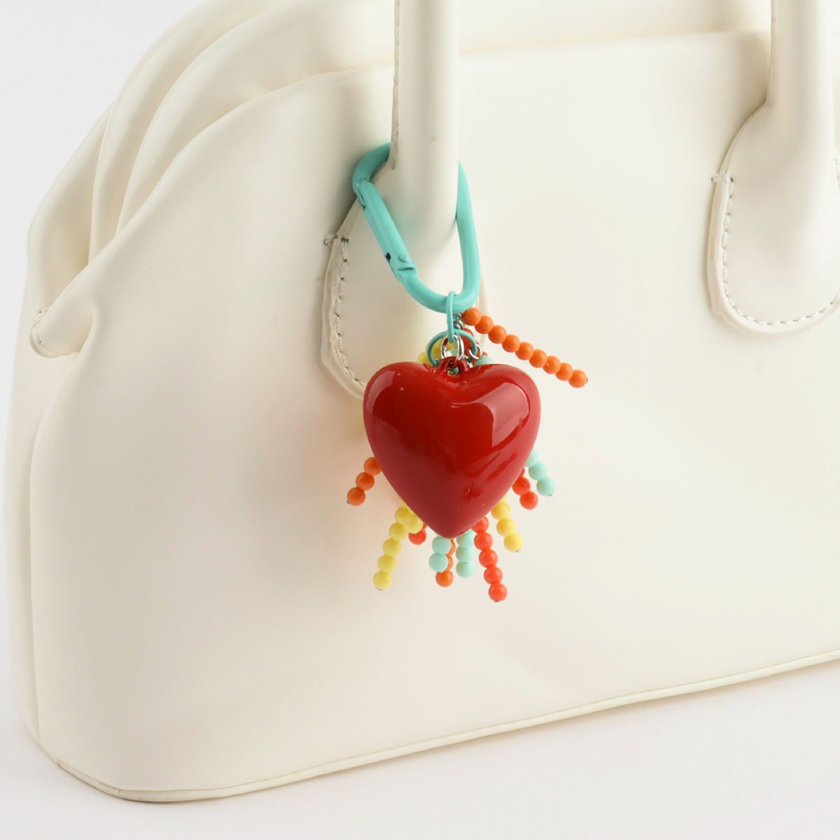 Handmade heart beaded keychain attached to white bag - Y2K colorful bag charm with rainbow tassels