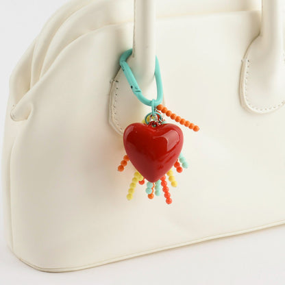 Handmade heart beaded keychain attached to white bag - Y2K colorful bag charm with rainbow tassels