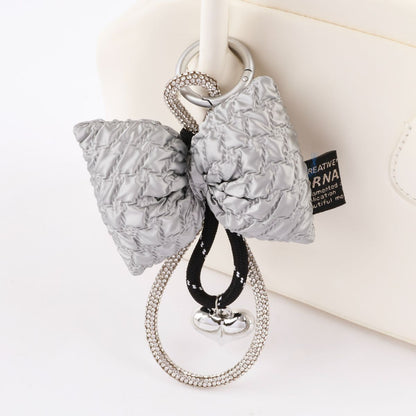 Close up of silver quilted bow keychain with rhinestone loop and heart charm detail