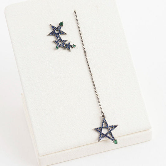 Flat lay of blue star drop earrings showing asymmetrical pair design and chain length
