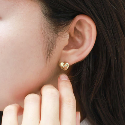 Side angle of gold heart stud earrings with designer-inspired quilted texture on ear