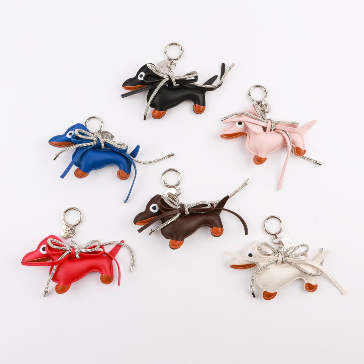 Six colorful handmade leather Dachshund keychains in black, blue, red, brown, pink, and white with crystal bows