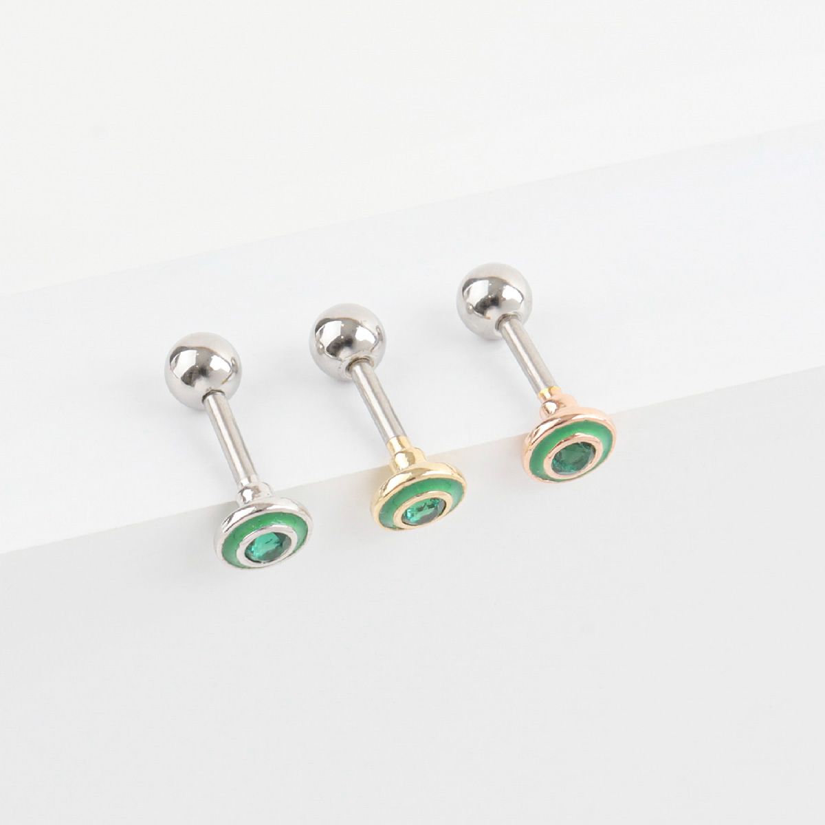 Close-up of green cubic cartilage earrings in three colors