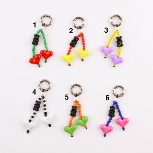  Six color options of handmade heart and gummy bear beaded keychains displayed flat - red green, yellow red, purple yellow, white black, green orange, pink blue