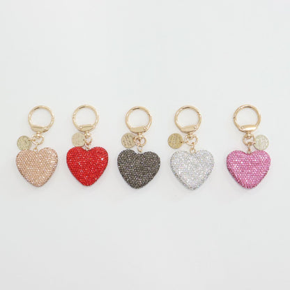 Top-down view of five rhinestone heart keychains arranged in a row.
Each has a gold keyring and a small gold medallion.