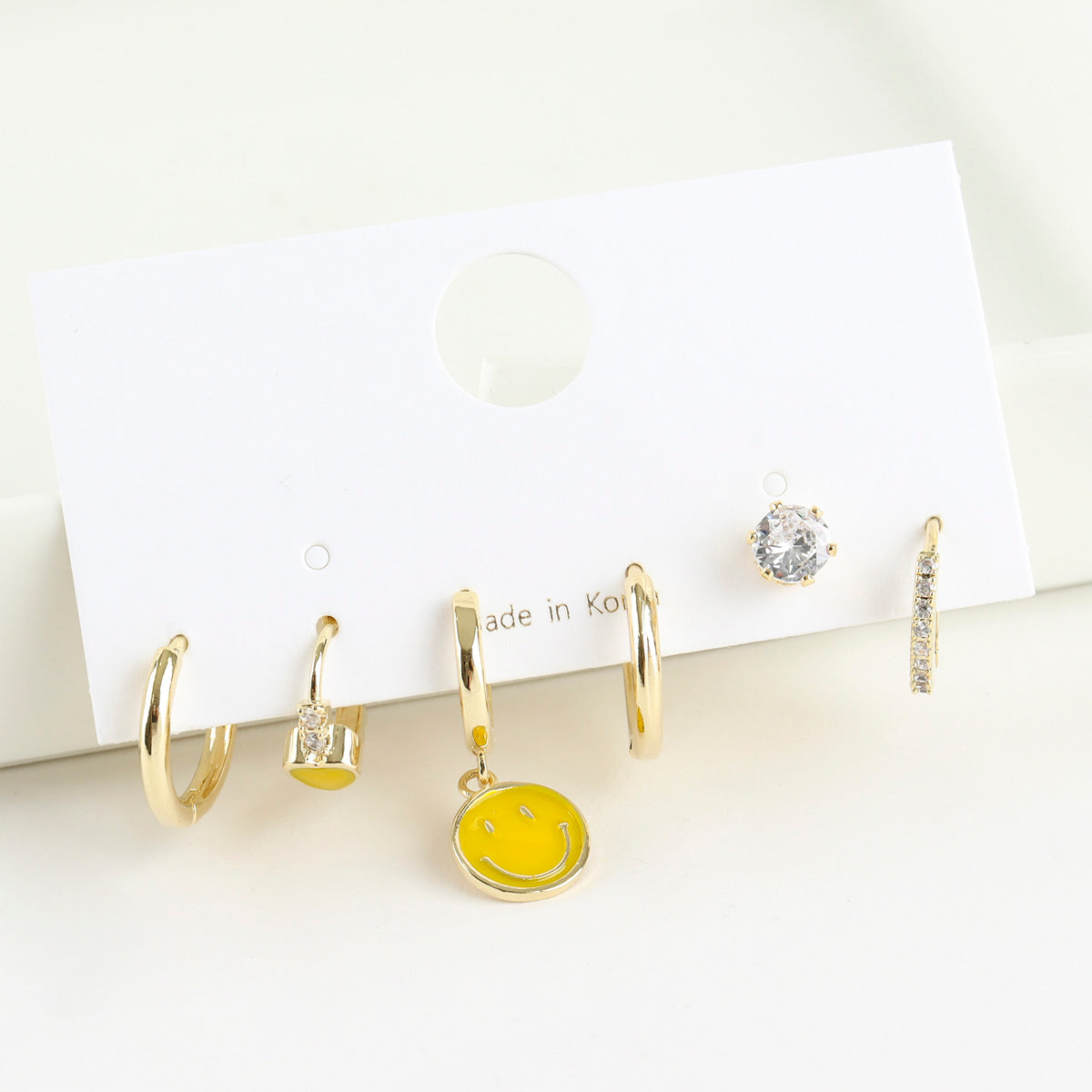 Smiley face hoop earring set with three asymmetric drop hoops on card