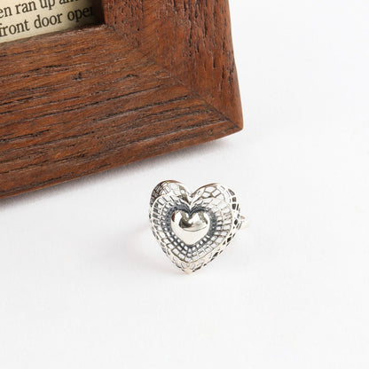 925 sterling silver filigree heart ring displayed on white background next to wooden frame showing front detail