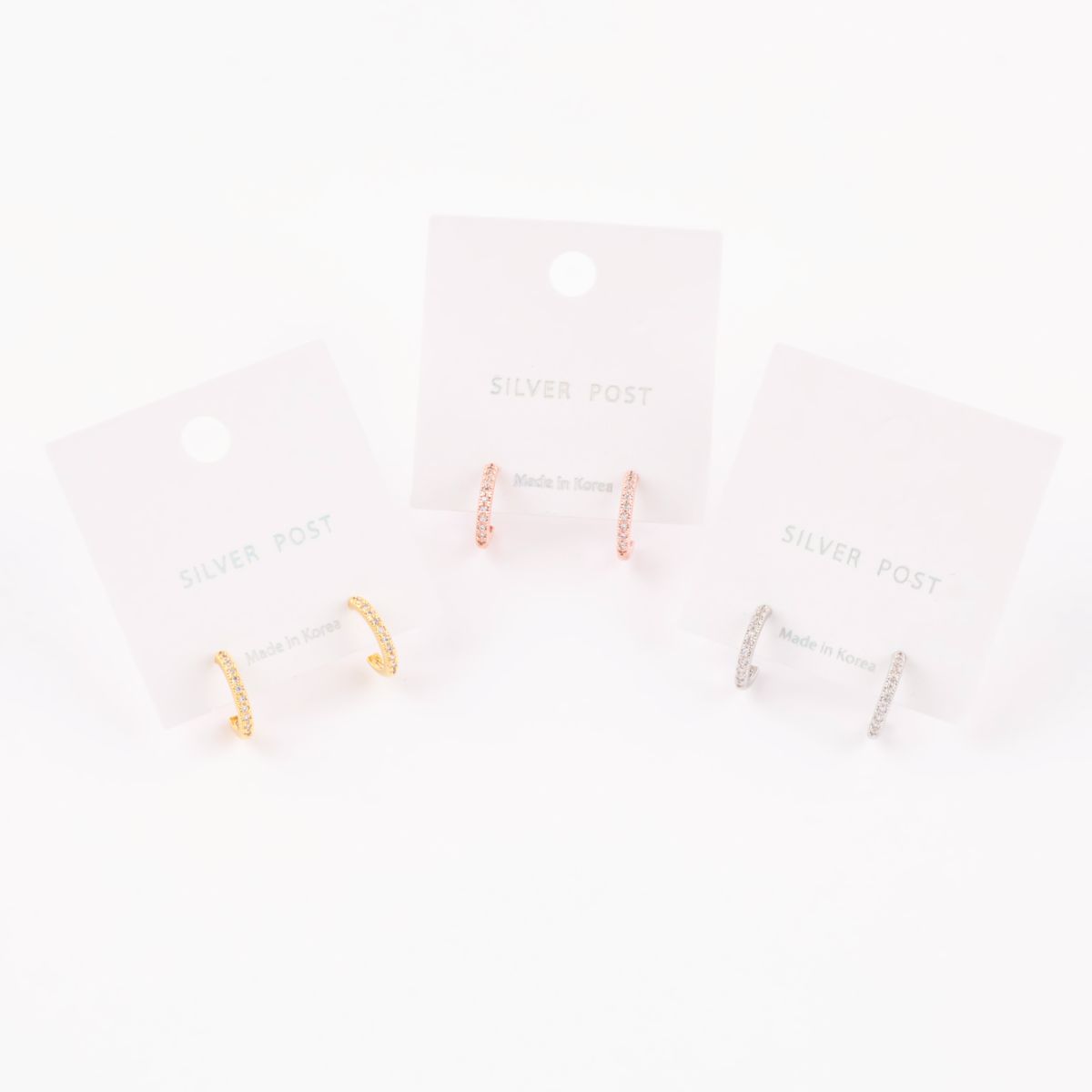 Three pairs of mini hoop earrings in gold, rose gold, and silver, mounted on 'Silver Post – Made in Korea' display cards.
