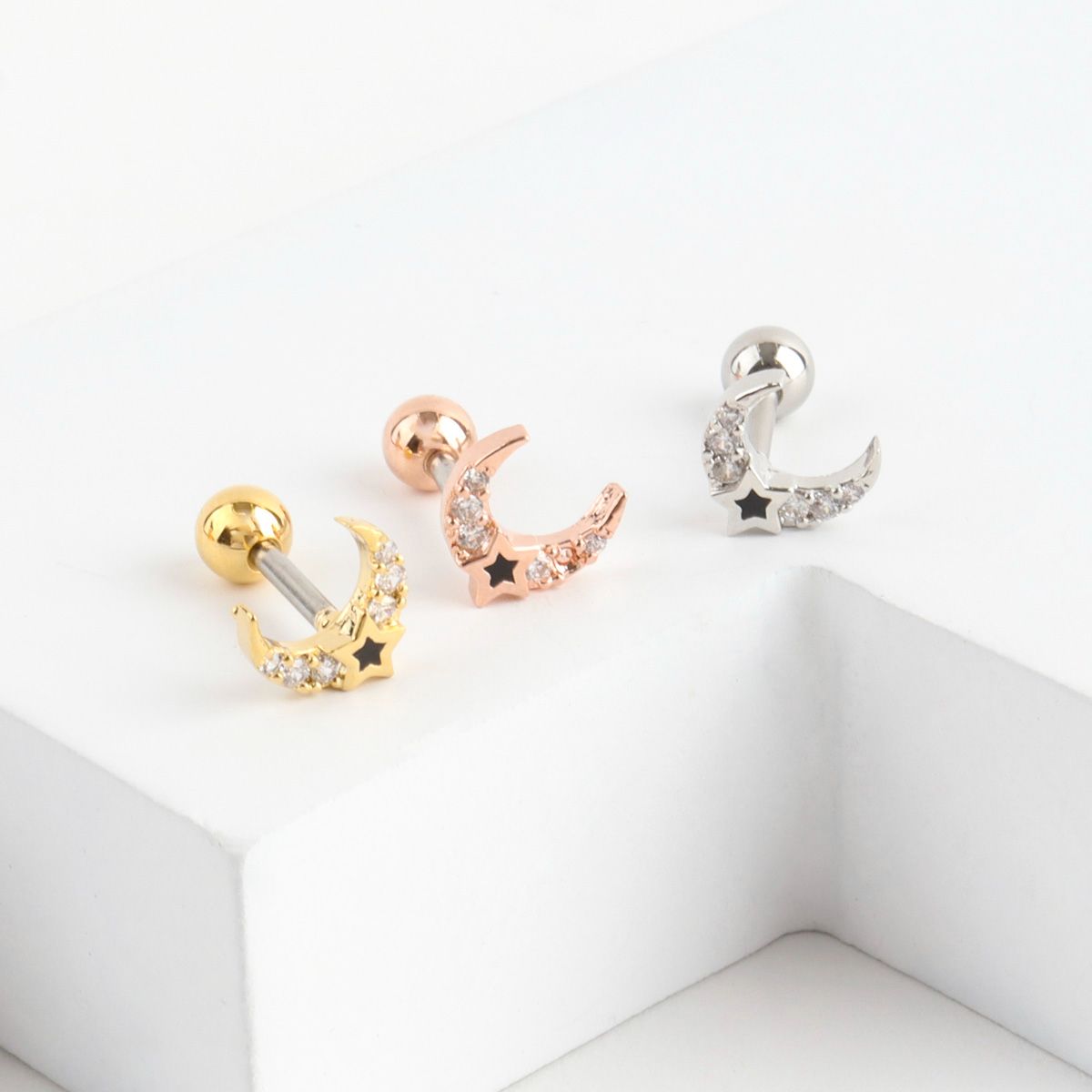 Product display of three crescent moon earrings in gold, rose gold, and silver, with star cutouts and cubic zirconia detailing.
