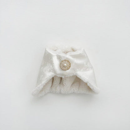Close-up of a white Korean jobawi baby bonnet with floral jacquard satin and gold pearl brooch.
