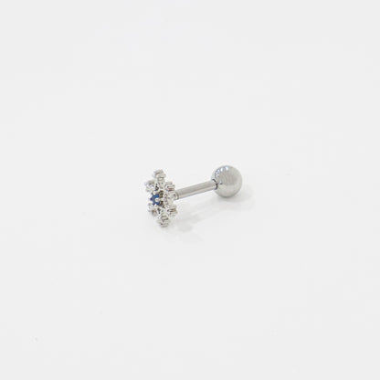 Angled view of silver snowflake barbell earring placed on white surface.
