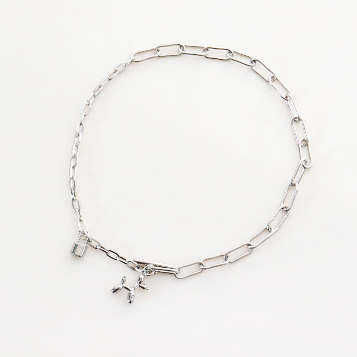 Flat lay of surgical steel toggle clasp necklace with paperclip chain and balloon dog charm