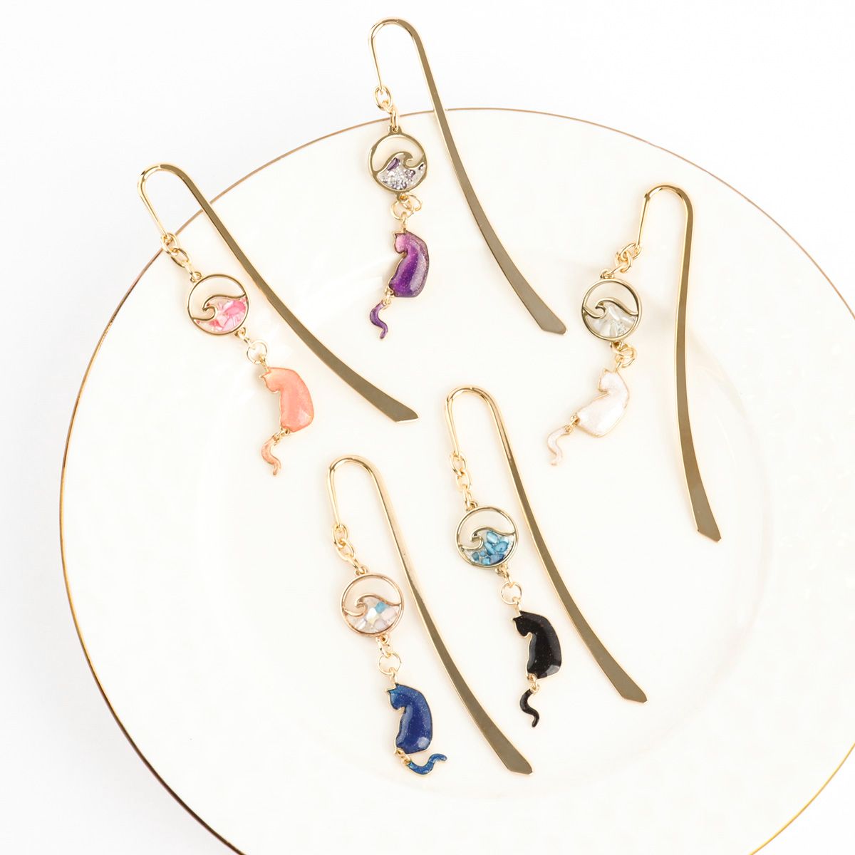 Gold metal cat bookmarks with wave charms displayed in circular arrangement showing all five elegant colors