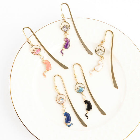 Gold metal cat bookmarks with wave charms displayed in circular arrangement showing all five elegant colors