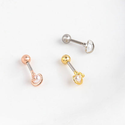 Flat lay of three Saturn planet pearl orbit barbell piercings in silver, gold, and rose gold with replaceable back balls
