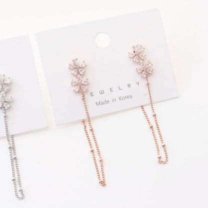 Close-up detail shot of rose gold flower CZ earrings with chain on card