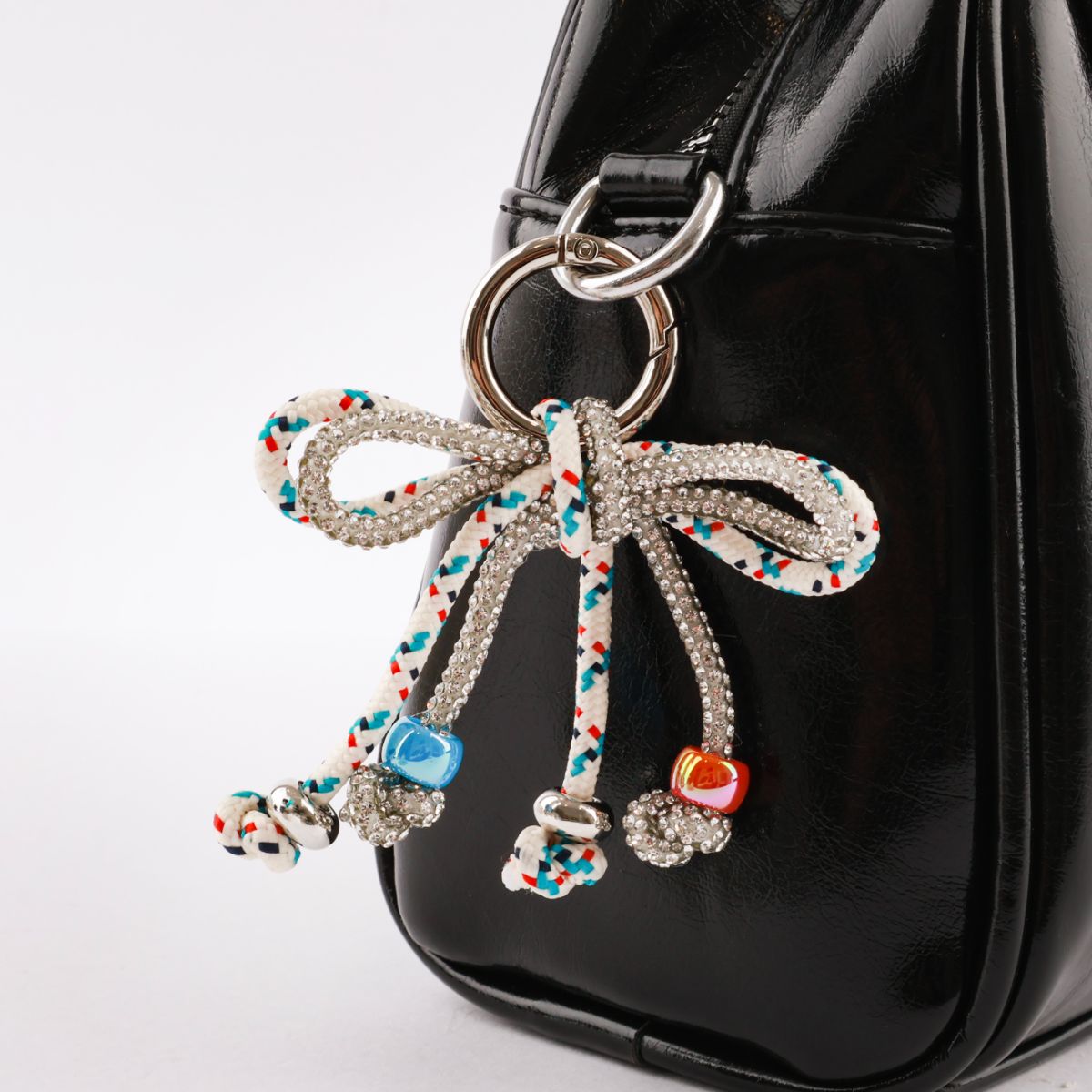 Black patent leather bag with white multi dot rope bow charm and heart pendant detail