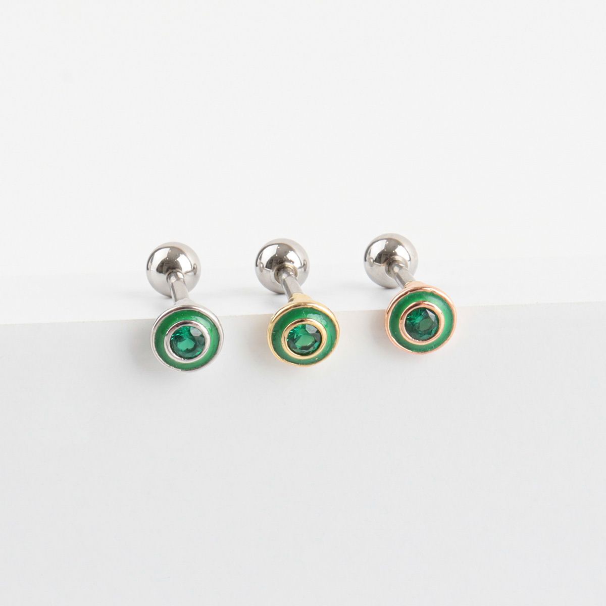 Green cubic barbell earrings displayed on white surface
