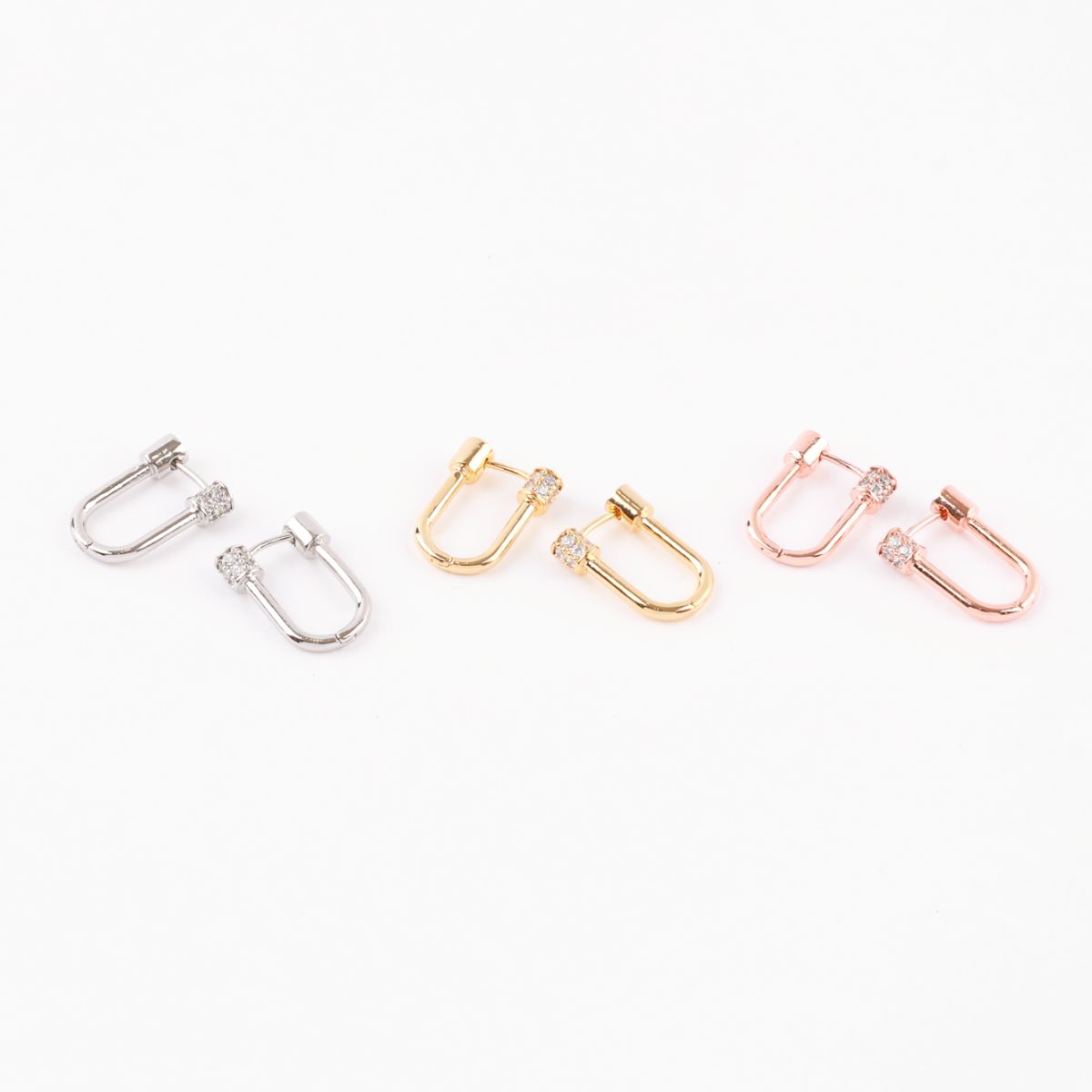 Three pairs of hoop earrings in silver, gold, and rose gold with pavé cylinder clasps arranged side by side on a white background.